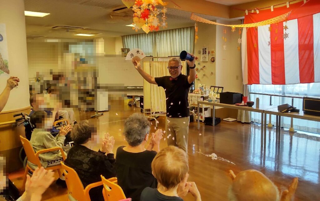 大阪市鶴見区の老人施設でのボランティア・マジックショー。紙うどんというマジックの最後に桜吹雪をまいています。