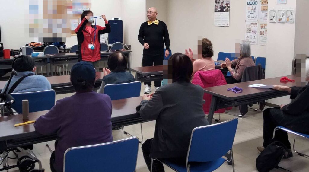 大阪市西区の九条会館でのボランティア・マジックショーとマジック教室をしました。消える蝶々結びのマジックの説明をしているところです。