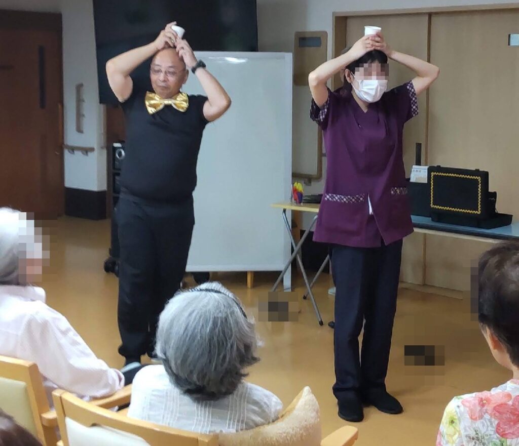 大阪の老人施設でのボランティア・マジックショー。頭の上のカップの水がいつのまにか消えてしまうマジックです。