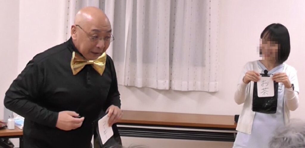 大阪府寝屋川市の自治会でのボランティア・マジックショー。お茶とコーヒーを一瞬で入れ替えるマジックを披露しています。