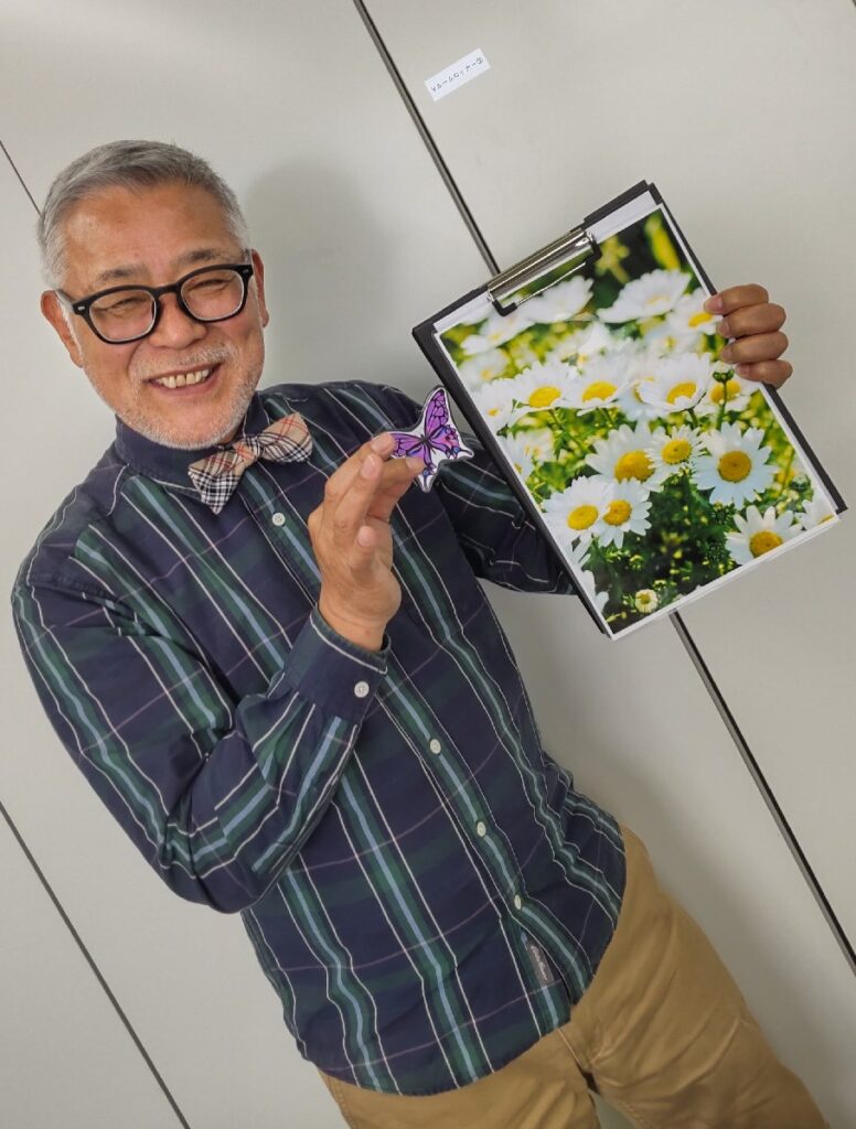  バインダーを開くときれいなお花畑の写真が一枚はさんであります。ひげ親父が空中の何かを掴んでその写真にかざすと、お花畑の中に蝶々の写真が現れます。次にバインダーを一度閉じて息を吹きかけ、再びバインダーを開けると・・・蝶々が写真の中から・・・